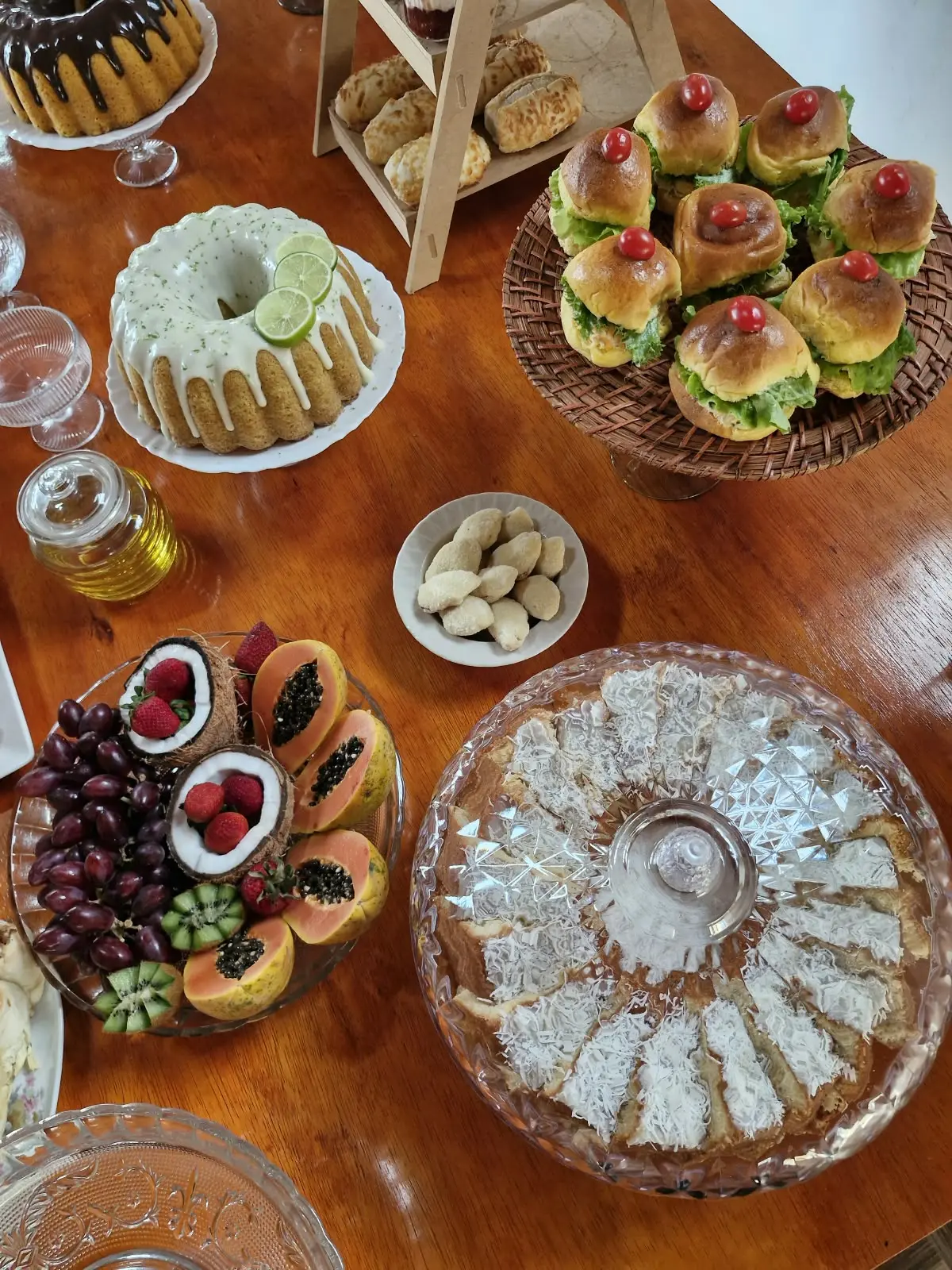 Mesa vista de cima com bolos, frutas, salgados e cocada