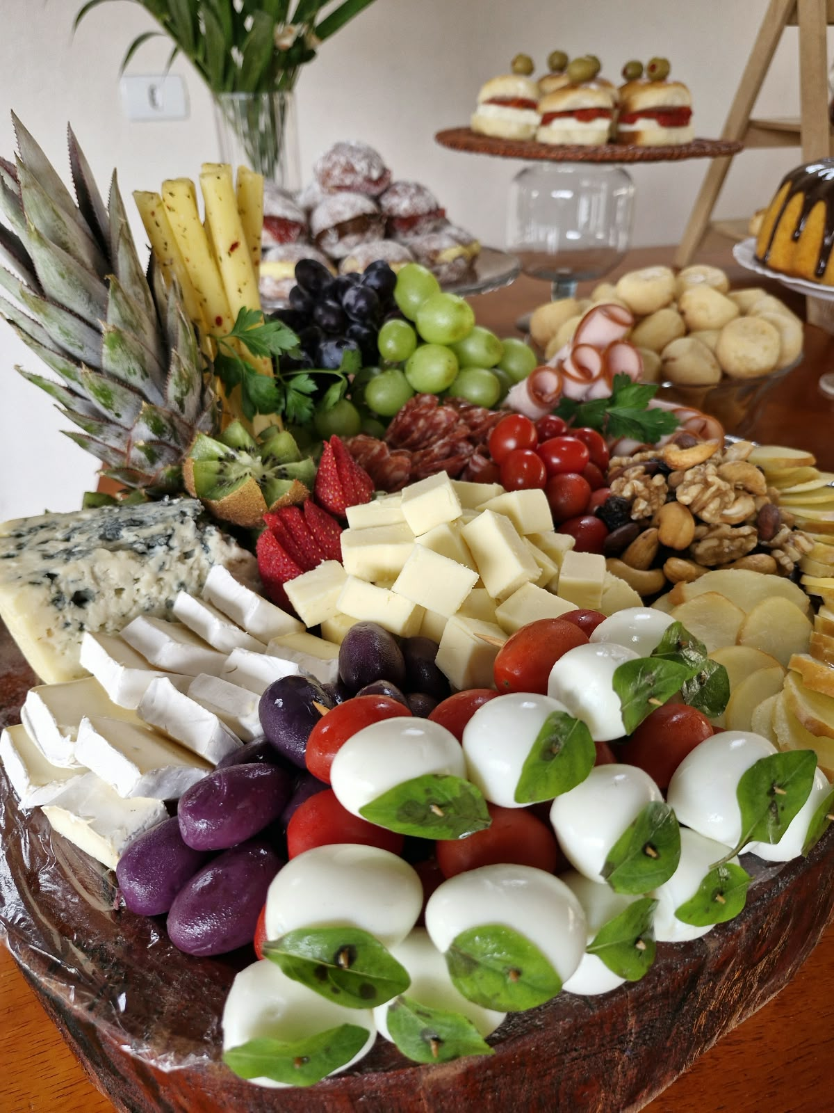 Tábua de finger foods com queijos, frutas e acompanhamentos
